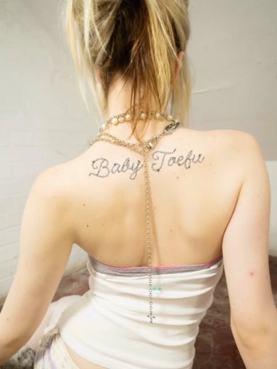 Baby Toefu glitter tattoo across a model's back with a chain necklace